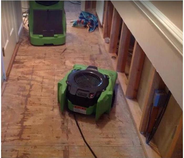 SERVPRO drying equipment being used in water damaged room; flood cuts along walls